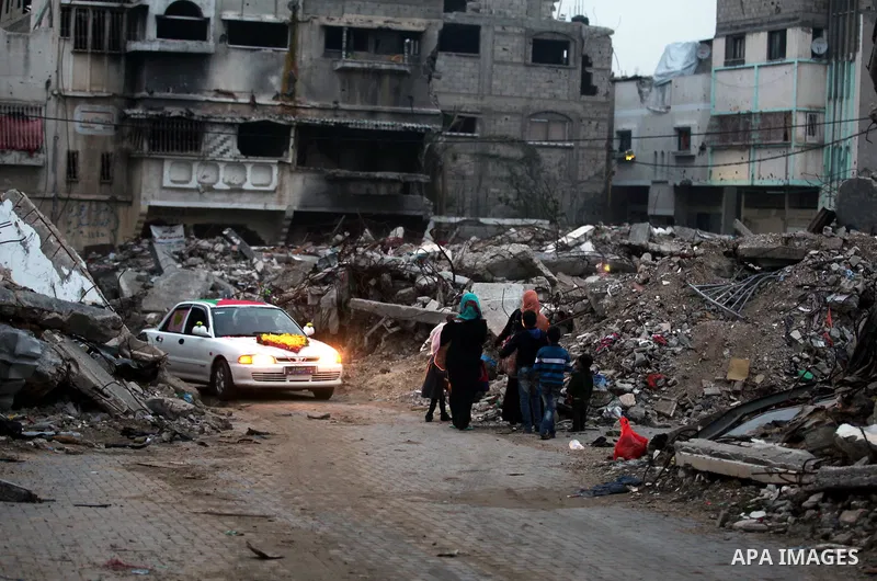 Palestinians walk past the rubbles of houses, which were destroyed during the recent Israeli offensive on Gaza Strip, in Shijaiyah neighborhood, east Gaza City, December 8, 2014. According to housing minister Mufeed al-H...