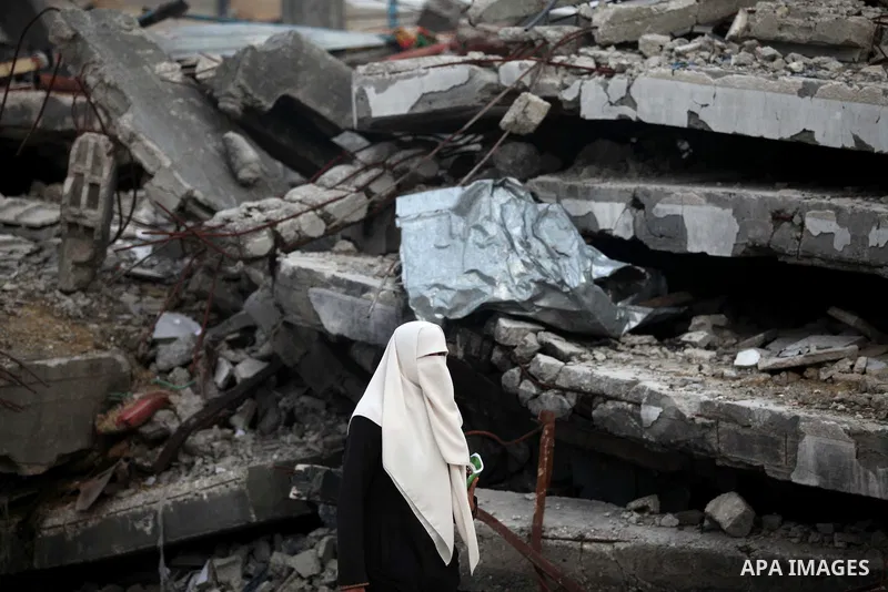 A Palestinian woman walks past the rubbles of houses, which were destroyed during the recent Israeli offensive on Gaza Strip, in Shijaiyah neighborhood, east Gaza City, December 8, 2014. According to housing minister Muf...
