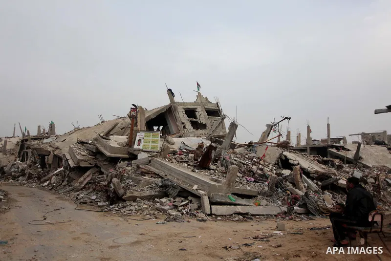 A Palestinian man sits in front of the rubbles of his house, which was destroyed during the recent Israeli offensive on Gaza Strip, in Shijaiyah neighborhood, east Gaza City, December 8, 2014. According to housing minist...