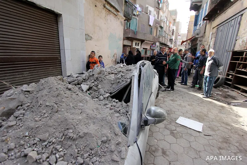 Egyptians and rescue workers inspect the site of a collapsed two-storey building in the Cairo district of Torgoman, December 9, 2014. The Ministry of Health and Population of Egypt injuring two people in the collapse of...