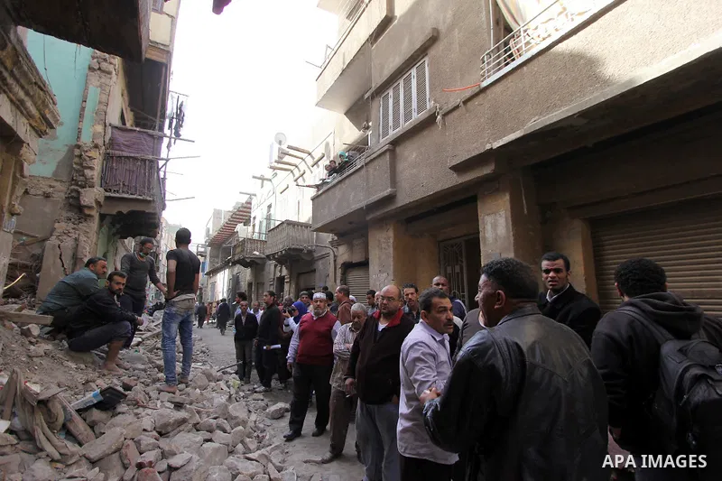 Egyptians and rescue workers inspect the site of a collapsed two-storey building in the Cairo district of Torgoman, December 9, 2014. The Ministry of Health and Population of Egypt injuring two people in the collapse of...
