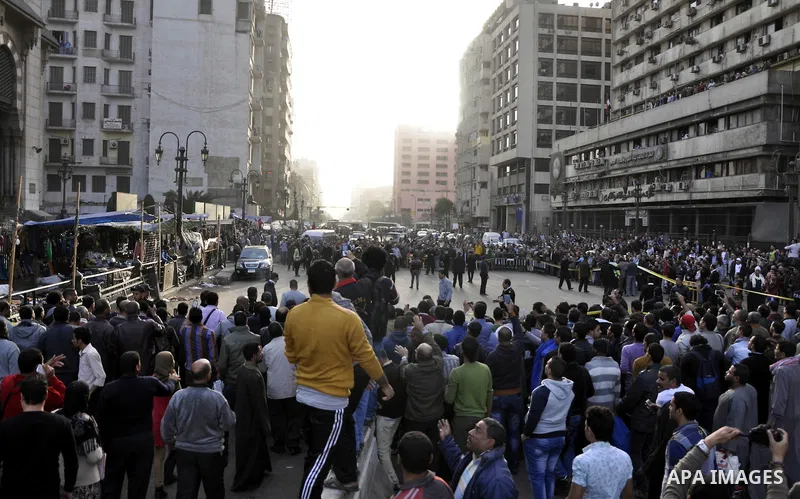 Egyptians and policemen stand at the scene as explosive experts try to dismantle a home-made bomb close to downtown Ramses Square, Cairo December 9, 2014. Egypt has seen a wave of bombings and shootings, mainly against a...