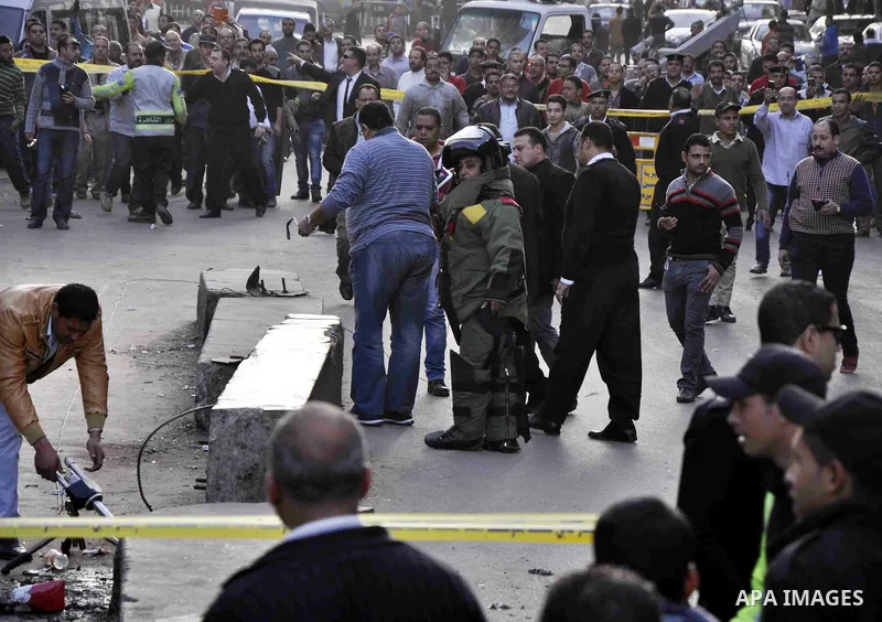 Egyptians and policemen stand at the scene as explosive experts try to dismantle a home-made bomb close to downtown Ramses Square, Cairo December 9, 2014. Egypt has seen a wave of bombings and shootings, mainly against a...