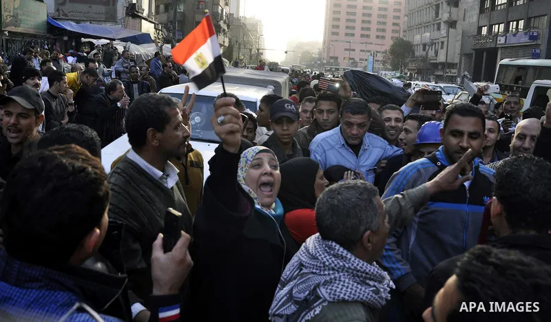 Egyptians and policemen stand at the scene as explosive experts try to dismantle a home-made bomb close to downtown Ramses Square, Cairo December 9, 2014. Egypt has seen a wave of bombings and shootings, mainly against a...