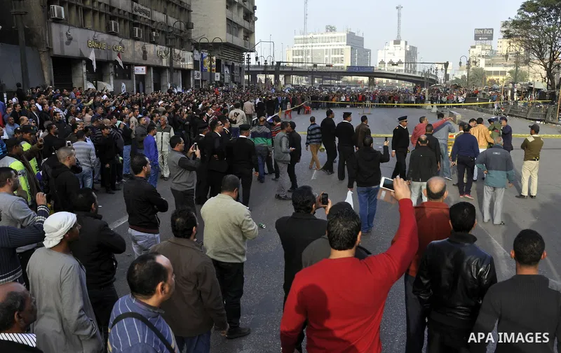 Egyptians and policemen stand at the scene as explosive experts try to dismantle a home-made bomb close to downtown Ramses Square, Cairo December 9, 2014. Egypt has seen a wave of bombings and shootings, mainly against a...