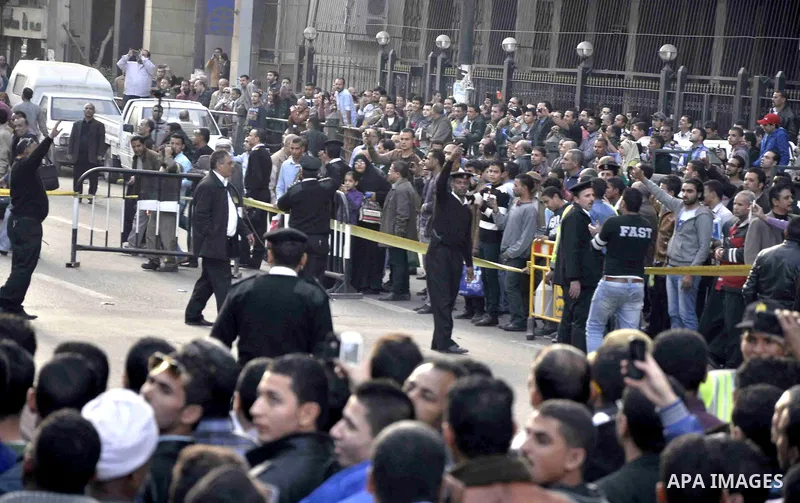 Egyptians and policemen stand at the scene as explosive experts try to dismantle a home-made bomb close to downtown Ramses Square, Cairo December 9, 2014. Egypt has seen a wave of bombings and shootings, mainly against a...