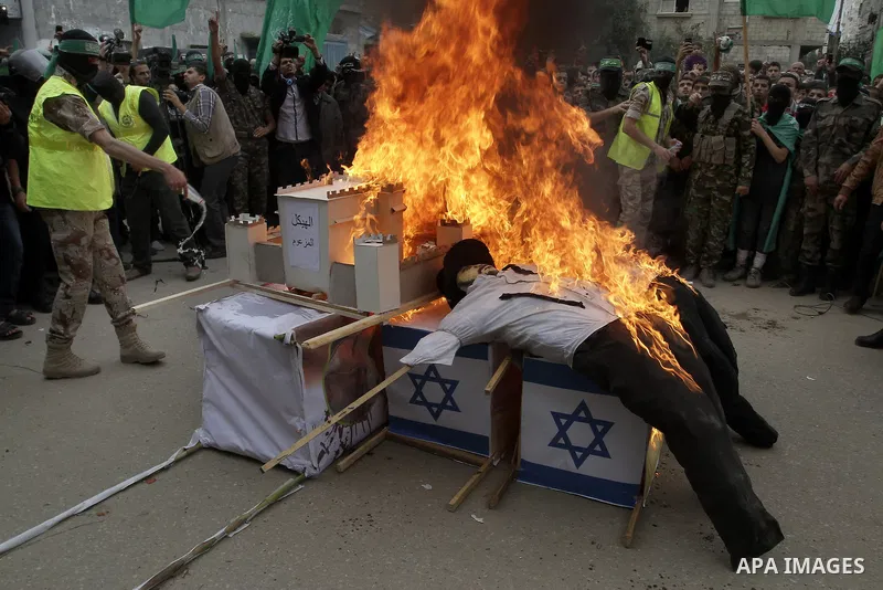 Palestinian militants from the Ezzedine al-Qassam brigade burn symbolic coffins with Israeli flags and effigies depicting Israeli settlers during a rally to commemorate the 27th anniversary of the Islamist movement s cre...