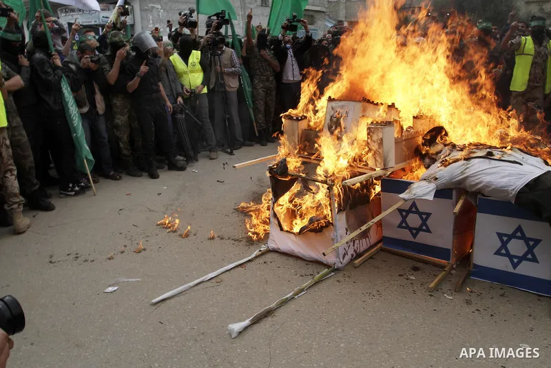Palestinian militants from the Ezzedine al-Qassam brigade burn symbolic coffins with Israeli flags and effigies depicting Israeli settlers during a rally to commemorate the 27th anniversary of the Islamist movement s cre...