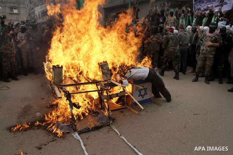 Palestinian militants from the Ezzedine al-Qassam brigade burn symbolic coffins with Israeli flags and effigies depicting Israeli settlers during a rally to commemorate the 27th anniversary of the Islamist movement s cre...