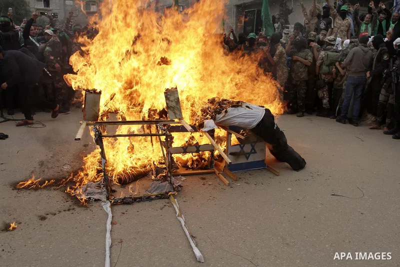 Palestinian militants from the Ezzedine al-Qassam brigade burn symbolic coffins with Israeli flags and effigies depicting Israeli settlers during a rally to commemorate the 27th anniversary of the Islamist movement s cre...