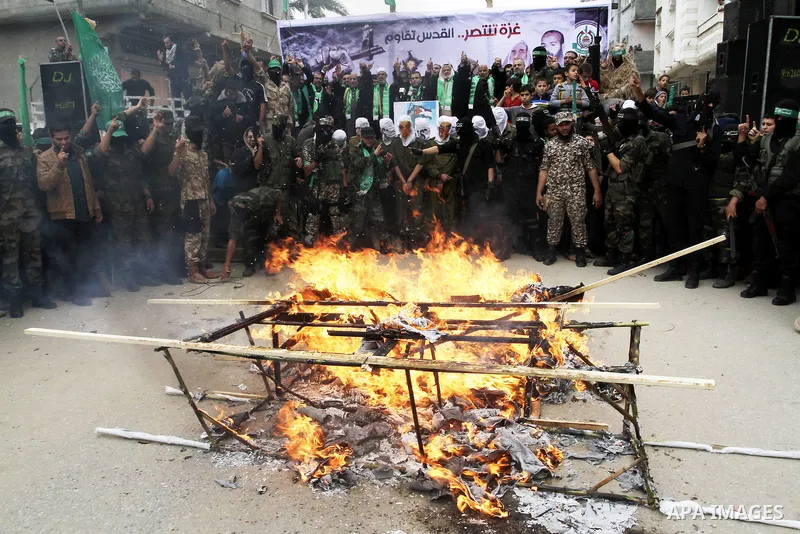 Palestinian militants from the Ezzedine al-Qassam brigade burn symbolic coffins with Israeli flags and effigies depicting Israeli settlers during a rally to commemorate the 27th anniversary of the Islamist movement s cre...