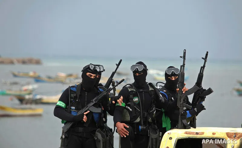 Palestinian members of al-Qassam Brigades, the armed wing of the Hamas movement, hold weapons as they take part in a military parade marking the 27th anniversary of Hamas' founding, in Gaza City December 14, 2014. Photo...