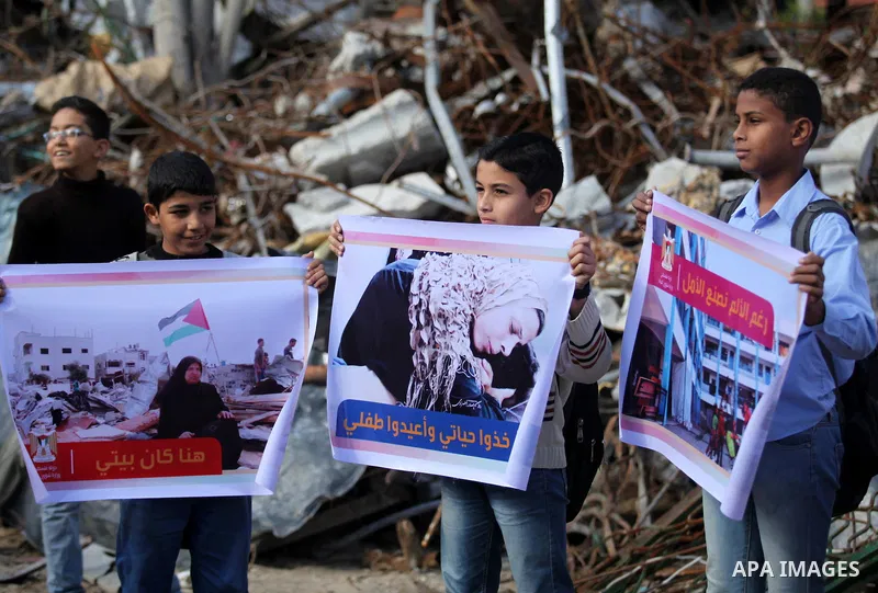 Palestinian children hold banners during a media conference organised by the ministry of women affairs in front of the Italian Complex, which was destroyed by Israeli air strike during the Israel-Gaza conflict, in Gaza c...
