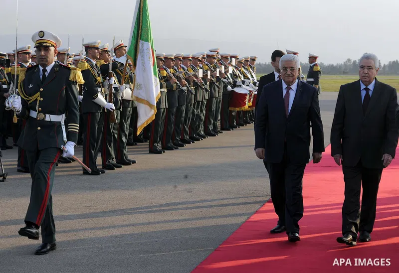 Palestinian president Mahmoud Abbas walks on the red carpet as he arrives at Houari Boumediene Airport outside the capital Algiers on December 21, 2014. Abbas is on a three-day official visit and he is expected to meet s...