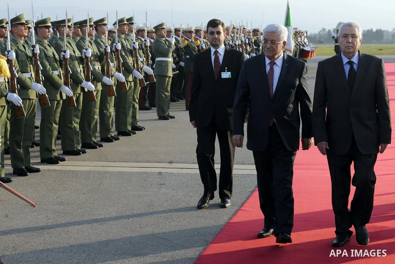 Palestinian president Mahmoud Abbas walks on the red carpet as he arrives at Houari Boumediene Airport outside the capital Algiers on December 21, 2014. Abbas is on a three-day official visit and he is expected to meet s...