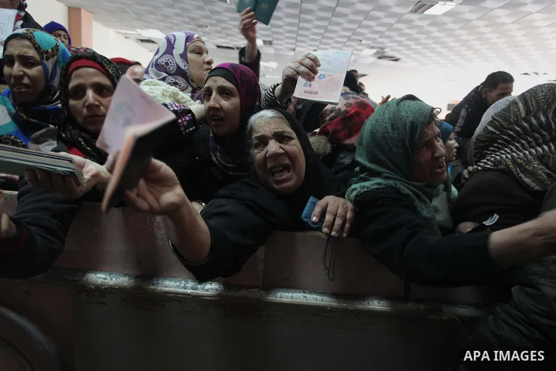 Palestinian women present their passports as they ask for permits to cross into Egypt at the Rafah border crossing between Egypt and the southern Gaza Strip December 23, 2014. Egypt opened the Rafah border crossing on Su...