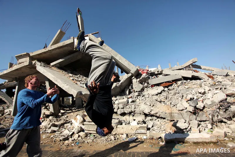 Palestinian youth practice parkour amid the rubble of houses which were destroyed during the recent Israeli offensive on Gaza Strip, in Shijaiyah neighborhood, east Gaza city December 25, 2014. Photo by Ashraf Amra