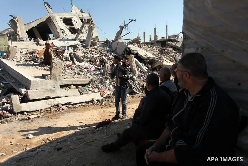 Palestinians sit in front their houses which were destroyed during the recent Israeli offensive on Gaza Strip, in Shijaiyah neighborhood, east Gaza city December 25, 2014. Photo by Ashraf Amra
