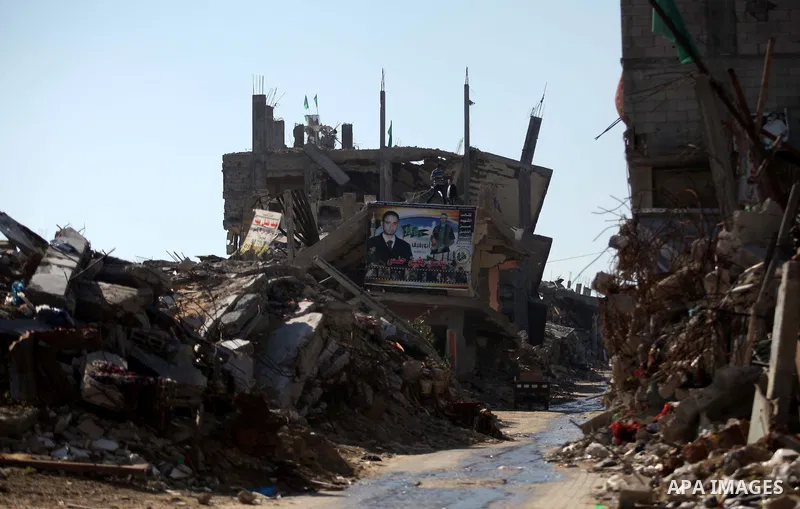 Palestinians hang a picture of their killed relative on the rubble of a house which was destroyed during the recent Israeli offensive on Gaza Strip, in Shijaiyah neighborhood, east Gaza city December 25, 2014. Photo by A...