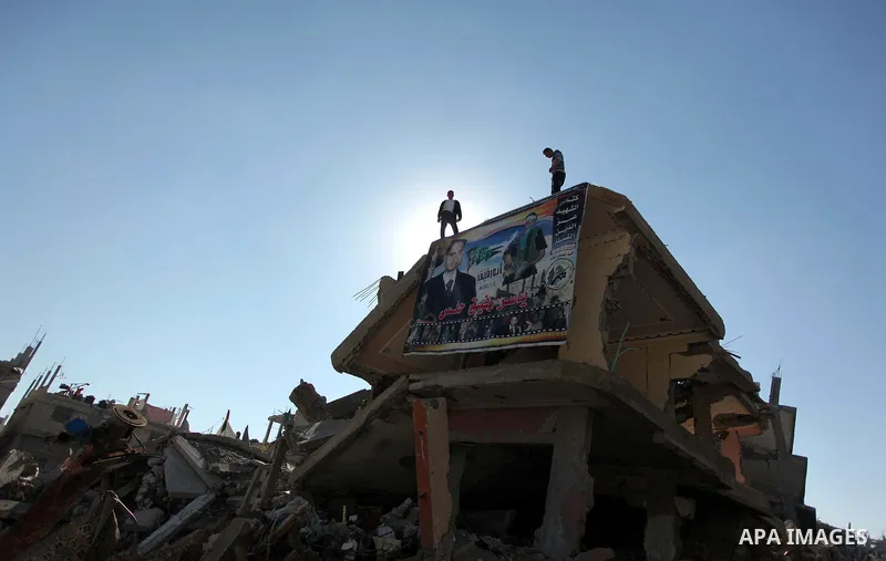 Palestinians hang a picture of their killed relative on the rubble of a house which was destroyed during the recent Israeli offensive on Gaza Strip, in Shijaiyah neighborhood, east Gaza city December 25, 2014. Photo by A...