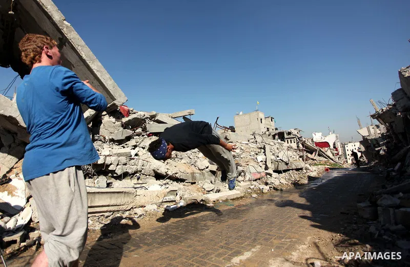 Palestinian youth practice parkour amid the rubble of houses which were destroyed during the recent Israeli offensive on Gaza Strip, in Shijaiyah neighborhood, east Gaza city December 25, 2014. Photo by Ashraf Amra