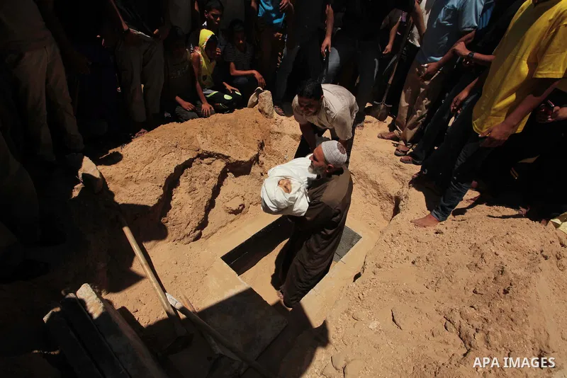 The grandfather and father of five-year-old boy Abdulrahman Khatab, who hospital officials said was killed in an Israeli air strike, bury his body in Deir El-Balah in the central Gaza Strip July 11, 2014. Fifteen people...