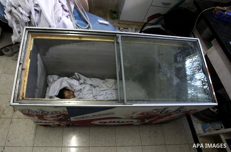 The body of two-and-a-half-year-old Palestinian girl Raghad Massoud, whom medics said was killed in an Israeli air strike, is seen inside an ice-cream freezer at Kuwaiti Hospital, which does not have a morgue, in Rafah i...