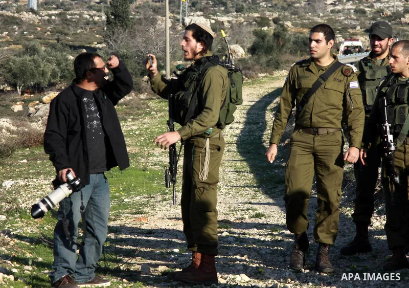An Israeli soldier argues with a Palestinian photojournalist as others stand guard at the scene where the Palestinian Imam Dwikat was shot dead by Israeli troops near the West Bank village of Beita near Nablus December 2...