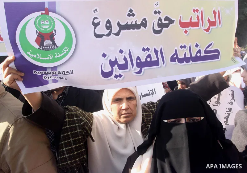 Palestinian employees of the former government in Gaza Strip hold banners during a protest to demanding their salaries, in front of the headquarters of the Council of Ministers in Gaza city, on December 30, 2014. Photo b...