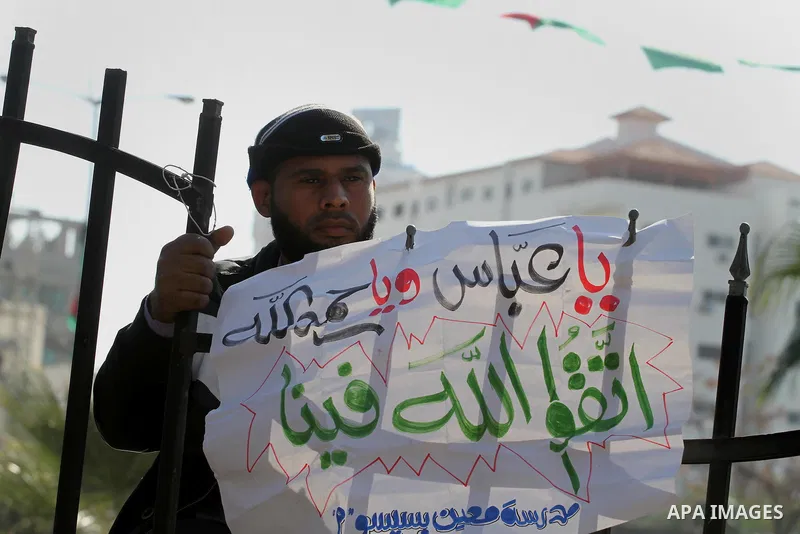 Palestinian employees of the former government in Gaza Strip hold banners during a protest to demanding their salaries, in front of the headquarters of the Council of Ministers in Gaza city, on December 30, 2014. Photo b...