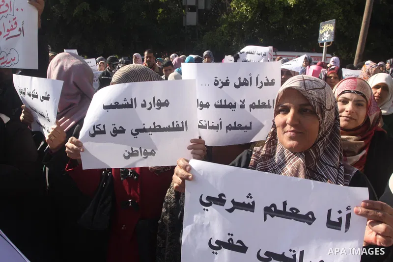 Palestinian employees of the former government in Gaza Strip hold banners during a protest to demanding their salaries, in front of the headquarters of the Council of Ministers in Gaza city, on December 30, 2014. Photo b...