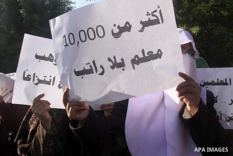 Palestinian employees of the former government in Gaza Strip hold banners during a protest to demanding their salaries, in front of the headquarters of the Council of Ministers in Gaza city, on December 30, 2014. Photo b...