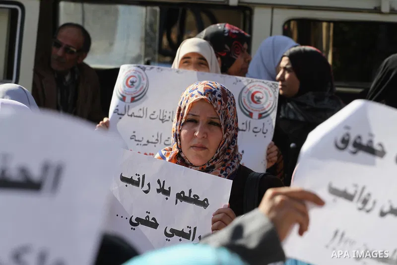 Palestinian employees of the former government in Gaza Strip hold banners during a protest to demanding their salaries, in front of the headquarters of the Council of Ministers in Gaza city, on December 30, 2014. Photo b...