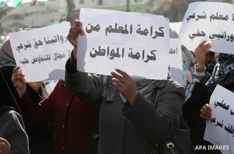 Palestinian employees of the former government in Gaza Strip hold banners during a protest to demanding their salaries, in front of the headquarters of the Council of Ministers in Gaza city, on December 30, 2014. Photo b...