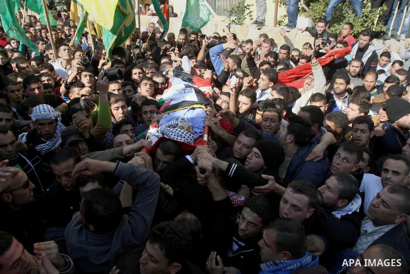 Mourners carry the body of 17-year-old Palestinian teenager Omam Dwekat, who was shot dead by Israeli troops the day before, during his funeral in the West Bank village of Baita, near of Nablus, on Dec. 30, 2014. Dwekat...