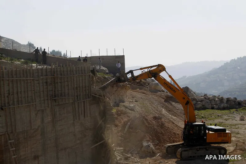 An Israeli bulldozer demolishes a building house at the Jabal al-Mukabbir village in the east of Jerusalem, December 30, 2014. Israeli authorities on Tuesday destroyed three homes, a restaurant, and a butcher shop in Jer...
