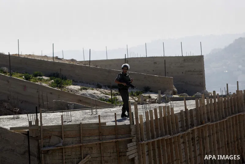 An Israeli security forces stands guard as a bulldozer demolishes a building house at the Jabal al-Mukabbir village in the east of Jerusalem, December 30, 2014. Israeli authorities on Tuesday destroyed three homes, a res...