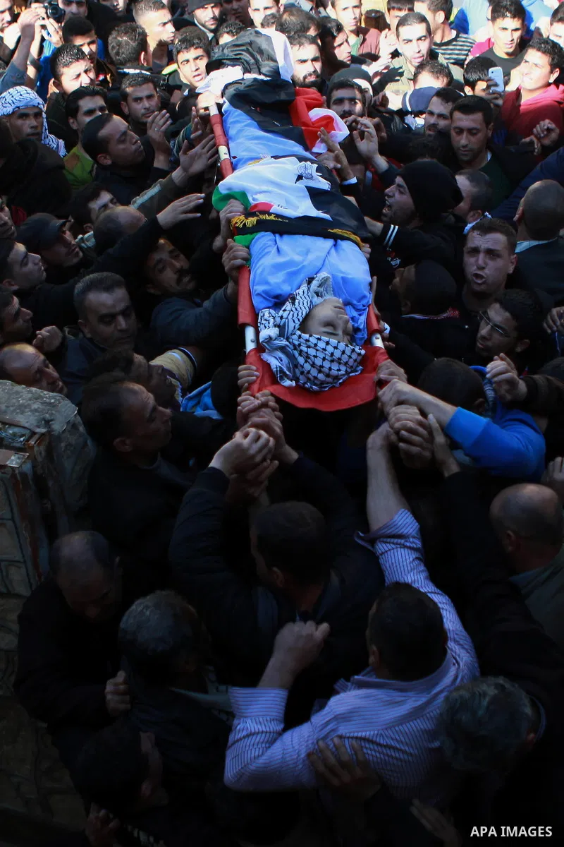Mourners carry the body of 17-year-old Palestinian teenager Omam Dwekat, who was shot dead by Israeli troops the day before, during his funeral in the West Bank village of Baita, near of Nablus, on Dec. 30, 2014. Dwekat...