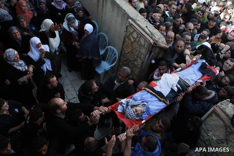 Mourners carry the body of 17-year-old Palestinian teenager Omam Dwekat, who was shot dead by Israeli troops the day before, during his funeral in the West Bank village of Baita, near of Nablus, on Dec. 30, 2014. Dwekat...