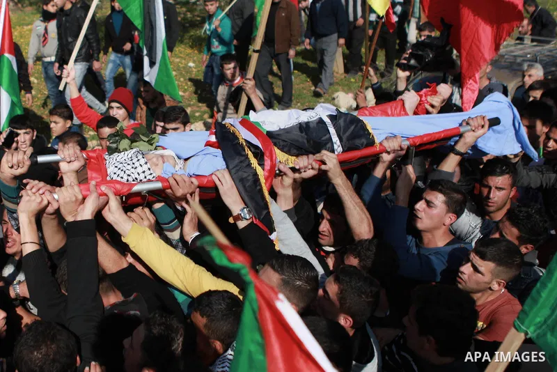 Mourners carry the body of 17-year-old Palestinian teenager Omam Dwekat, who was shot dead by Israeli troops the day before, during his funeral in the West Bank village of Baita, near of Nablus, on Dec. 30, 2014. Dwekat...