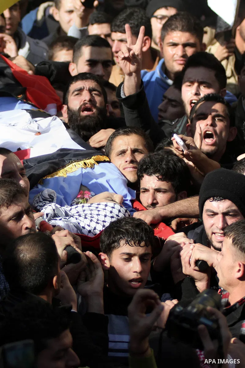 Mourners carry the body of 17-year-old Palestinian teenager Omam Dwekat, who was shot dead by Israeli troops the day before, during his funeral in the West Bank village of Baita, near of Nablus, on Dec. 30, 2014. Dwekat...