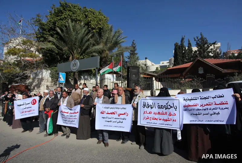 Palestinian families of martyrs hold placards during a protest to demand their rights, in front of the headquarters of the Council of Ministers in Gaza city, on December 31, 2014. Photo by Ashraf Amra