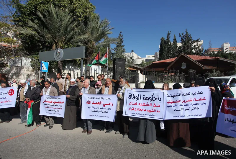 Palestinian families of martyrs hold placards during a protest to demand their rights, in front of the headquarters of the Council of Ministers in Gaza city, on December 31, 2014. Photo by Ashraf Amra