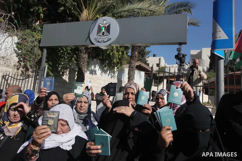 Palestinian women hold their passports during a protest demanding for the opening of Rafah crossing border in front of the headquarters of the Council of Ministers in Gaza city, on December 31, 2014. Photo by Ashraf Amra