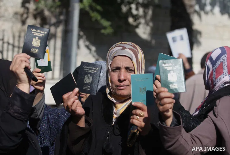 Palestinian women hold their passports during a protest demanding for the opening of Rafah crossing border in front of the headquarters of the Council of Ministers in Gaza city, on December 31, 2014. Photo by Ashraf Amra