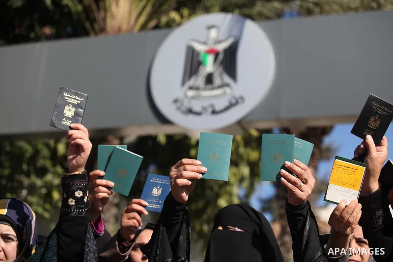 Palestinian women hold their passports during a protest demanding for the opening of Rafah crossing border in front of the headquarters of the Council of Ministers in Gaza city, on December 31, 2014. Photo by Ashraf Amra