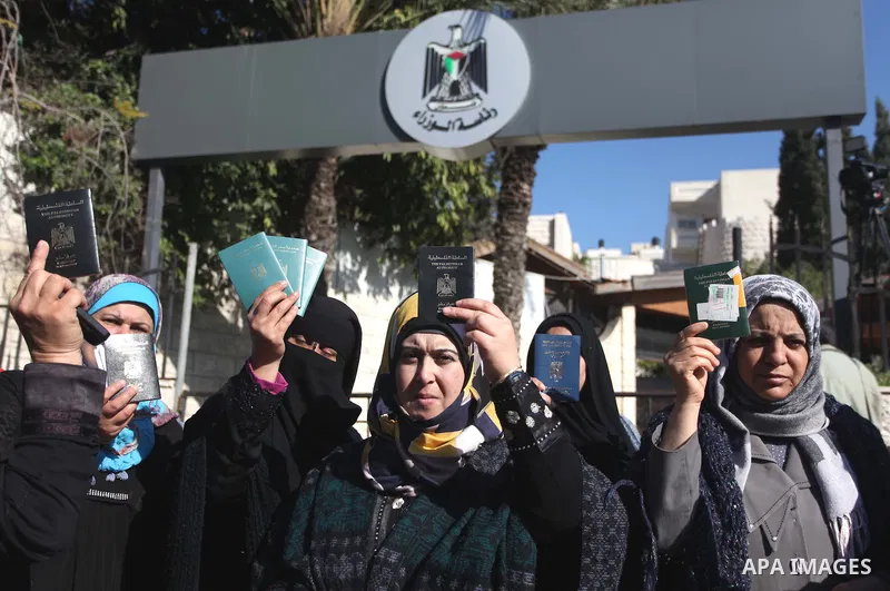 Palestinian women hold their passports during a protest demanding for the opening of Rafah crossing border in front of the headquarters of the Council of Ministers in Gaza city, on December 31, 2014. Photo by Ashraf Amra