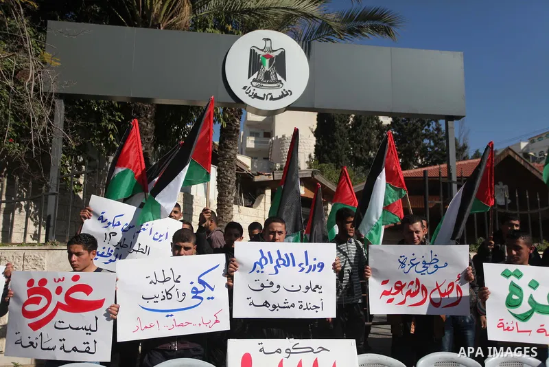 Palestinians hold posters during a rally organized as part of a general of the employees of former Palestinian government in Gaza Strip to demand for pay their salaries in front of the headquarters of the Council of Mini...