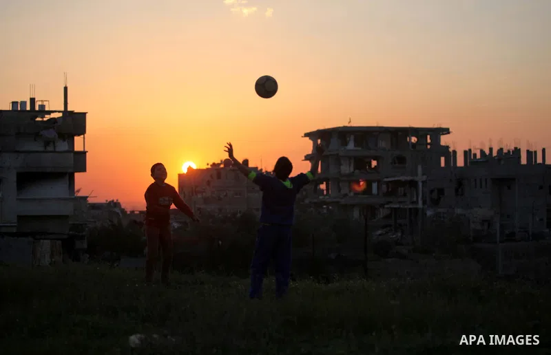 Palestinian youths play football in front of the rubbles of houses, which were destroyed during the recent Israeli offensive on Gaza Strip, in the last sunset of 2014, in Shijaiyah neighborhood, east Gaza city December 3...