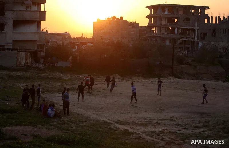 Palestinian youths play football in front of the rubbles of houses, which were destroyed during the recent Israeli offensive on Gaza Strip, in the last sunset of 2014, in Shijaiyah neighborhood, east Gaza city December 3...